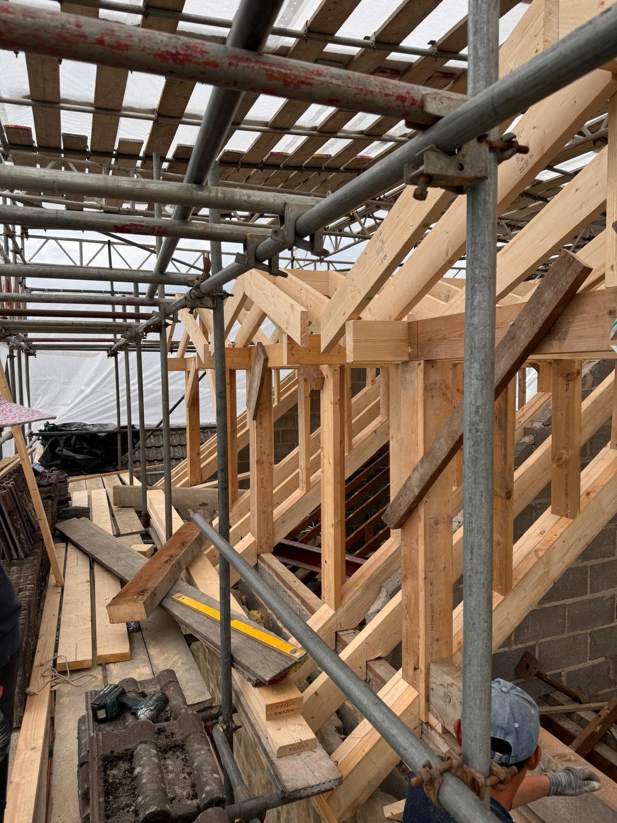 Before: the same dormer as bare timber structure — rafters, studwork and blockwork open to the scaffold sheeting overhead.